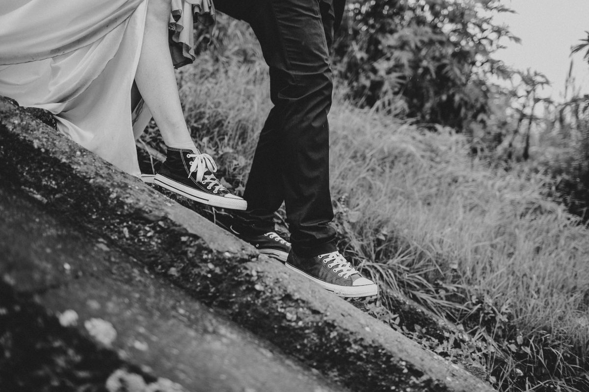 A married couple wearing sneakers traversing a hill.